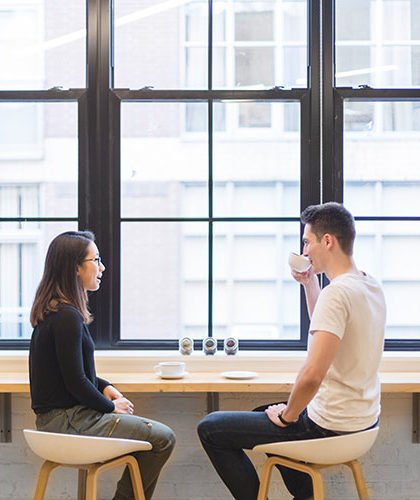 Two people talk over a coffee