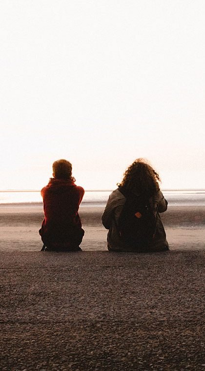 Two friends sitting by the beach
